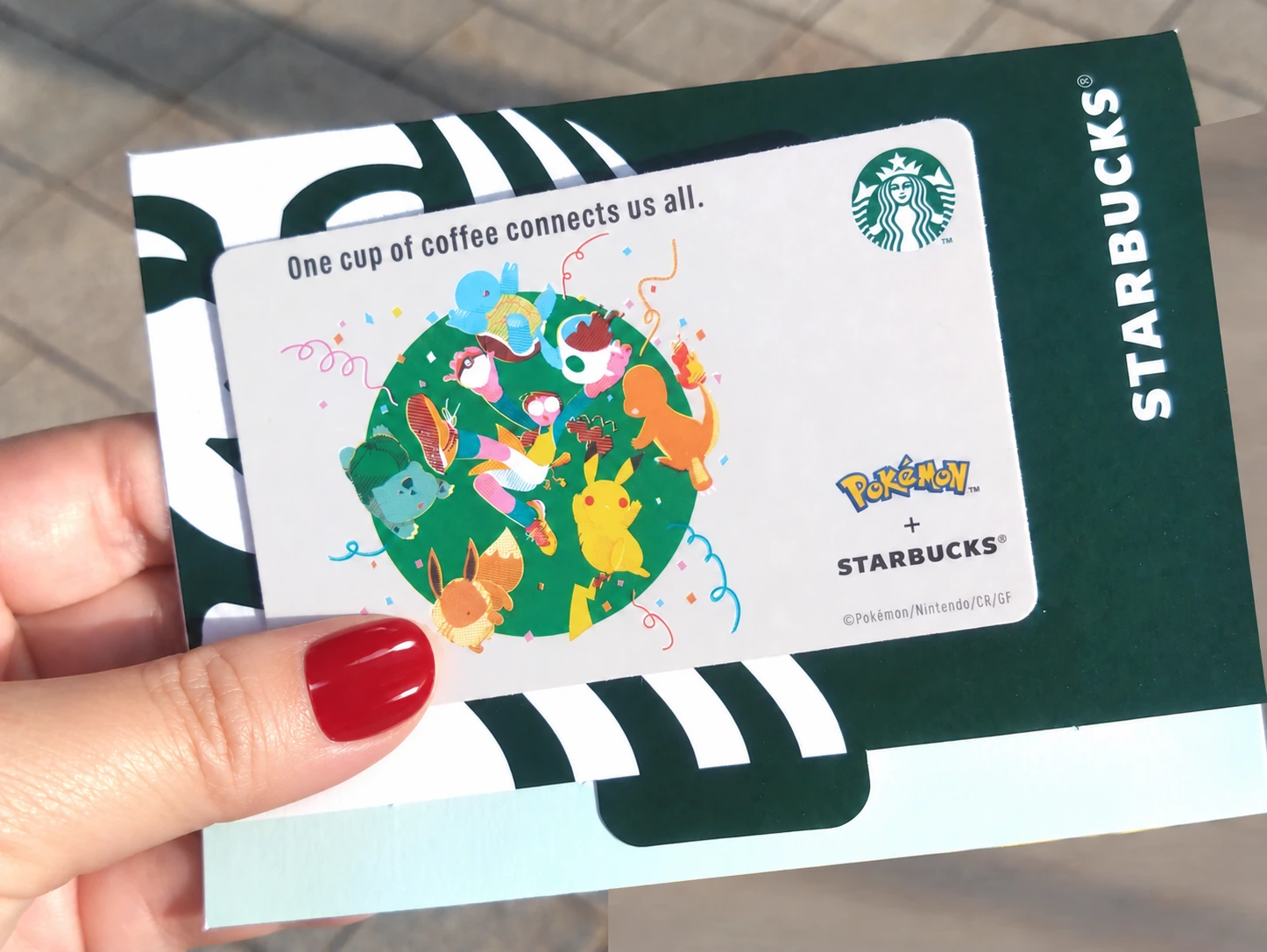 スタバ×ポケモンのスターバックスカード。ピカチュウ、イーブイ、ゼニガメ、フシギダネ、ヒトカゲが緑の円の中で遊ぶイラスト